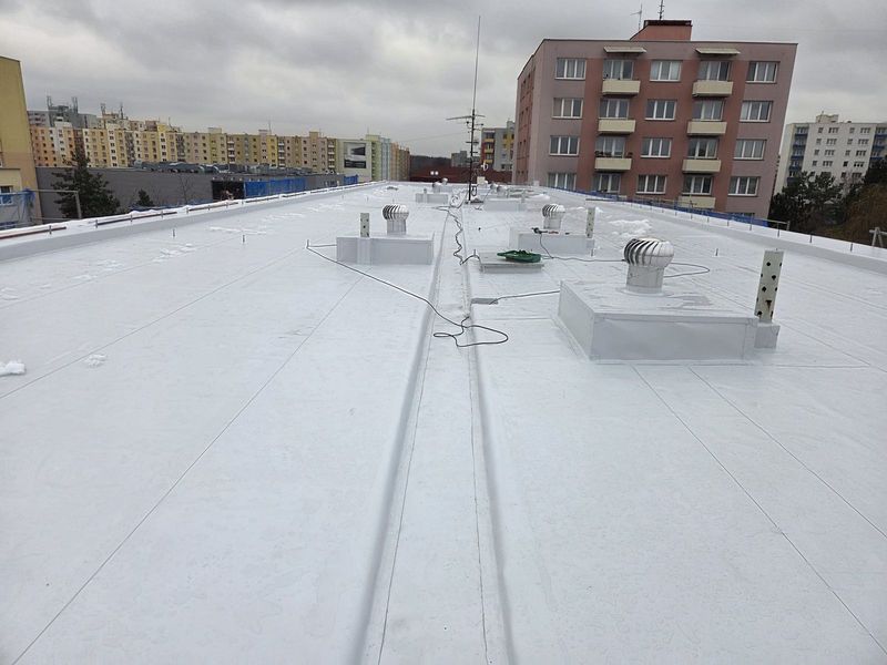 Fóliová střecha panelového domu s ventilačními hlavicemi